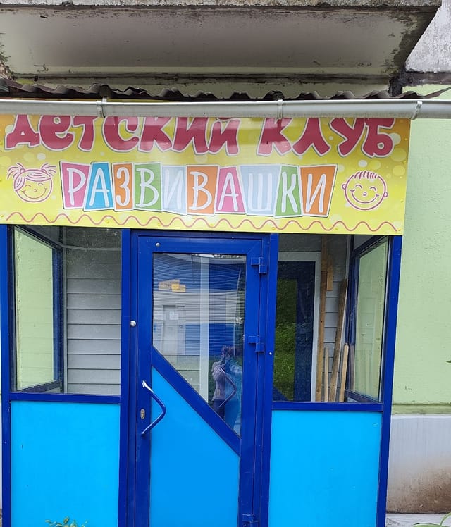 Вход в детский клуб «Развивашки» с вывеской и голубой дверью