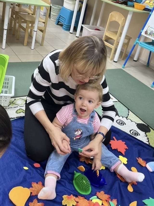 Мама с малышкой на коврике с осенними листьями