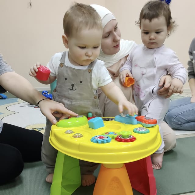 Малыши играют за развивающим столиком